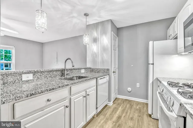 a kitchen with granite countertop stainless steel appliances a sink stove and cabinets
