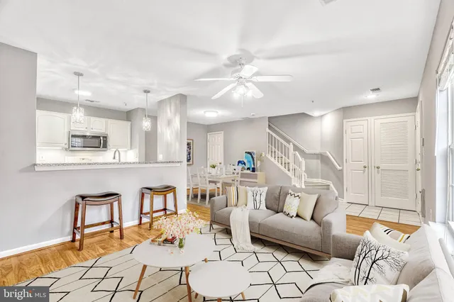 a living room with furniture kitchen view and a wooden floor