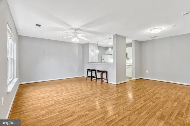 a view of an empty room with window and wooden floor