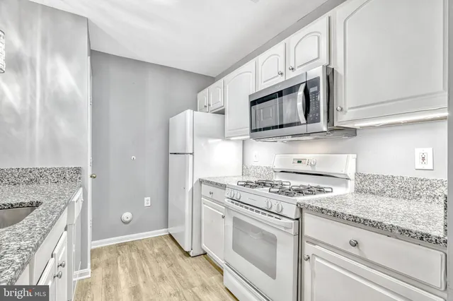 a kitchen with granite countertop cabinets stainless steel appliances and wooden floor