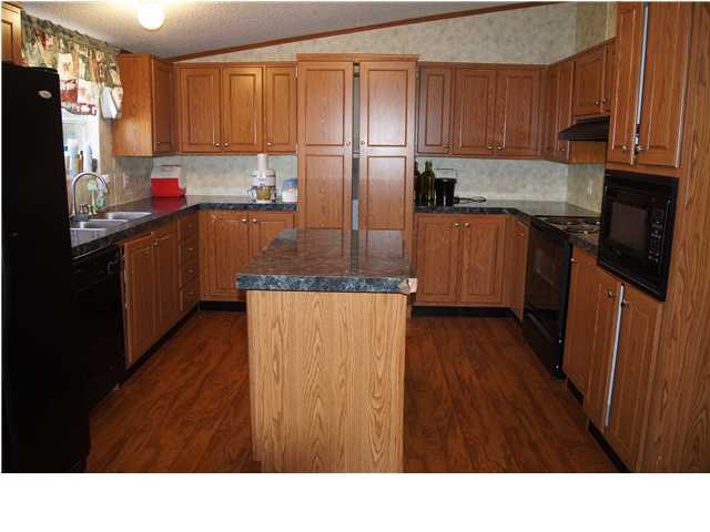 4493 Rainbird Rise Road Crestview, FL 32539 - Photo 7 of 27 a kitchen with stainless steel appliances a refrigerator and wooden cabinets
