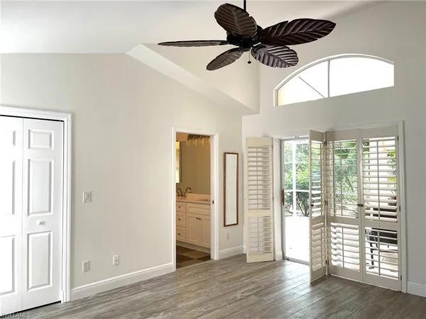 an empty room with wooden floor cabinet and windows