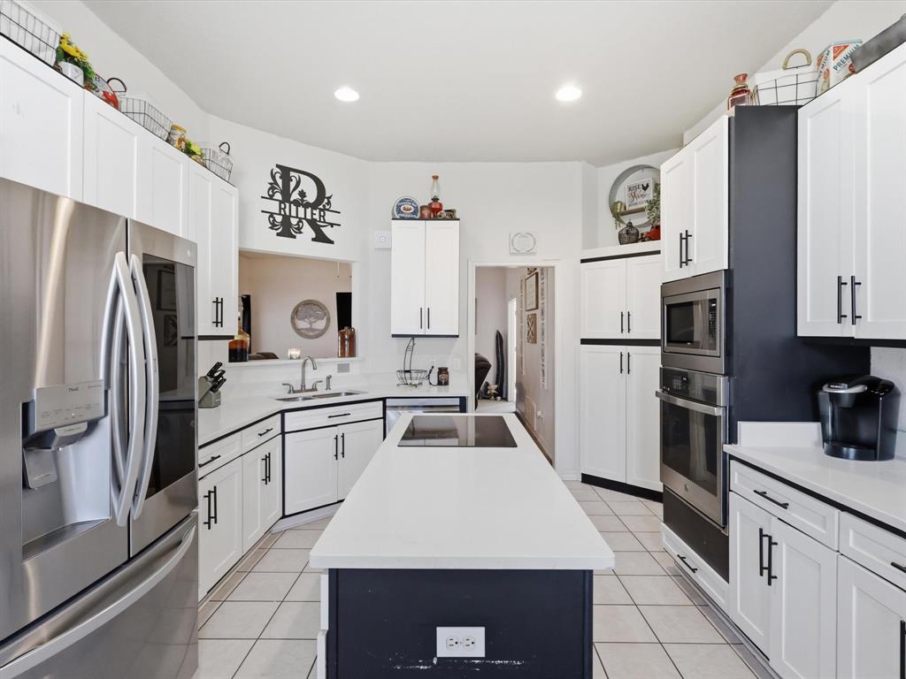 130 Parsonage Street Azle, TX 76020 - Photo 6 of 39 Kitchen with stainless steel appliances, a center island with sink, white cabinets, recessed lighting, and light tile patterned floors