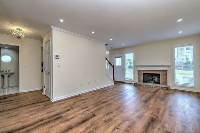 a view of an empty room with wooden floor fireplace and a window