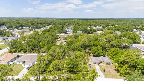 an aerial view of residential houses with outdoor space and trees