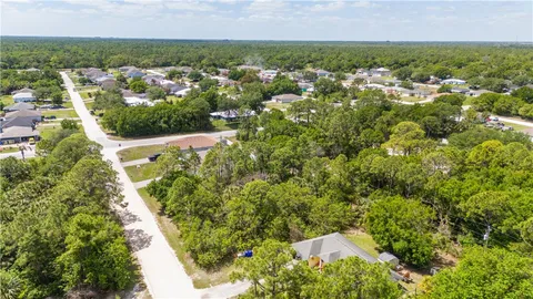 an aerial view of residential houses with outdoor space and trees all around