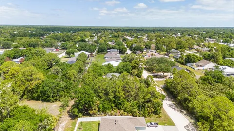 an aerial view of residential houses with outdoor space and trees