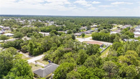 an aerial view of residential houses with outdoor space and trees