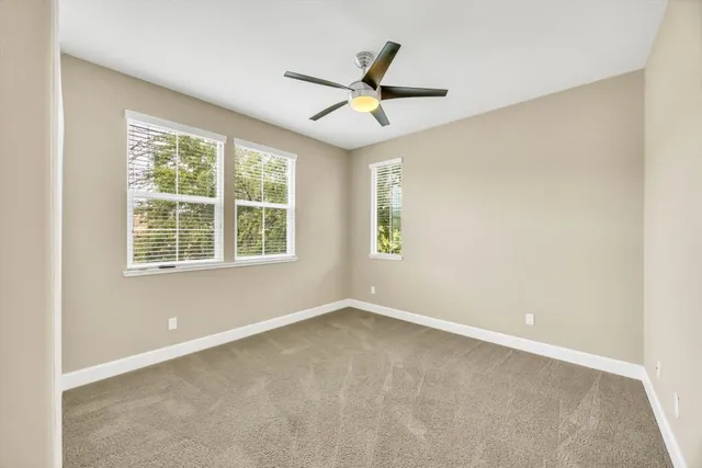 an empty room with window and ceiling fan