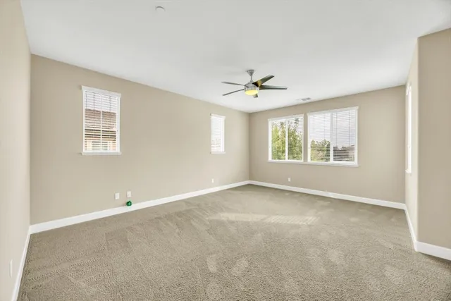 an empty room with windows and ceiling fan
