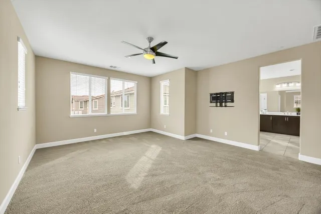 an empty room with windows and ceiling fan