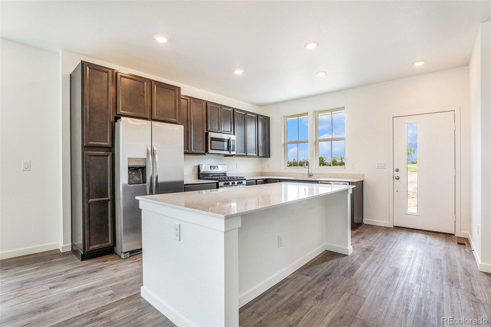 874 Furrow Way Lafayette, CO 80026 - Photo 24 of 27 a large kitchen with stainless steel appliances granite countertop a refrigerator a sink dishwasher a stove with wooden floors and cabinets