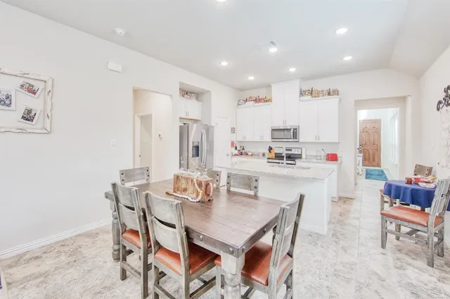 a dining room with kitchen island stainless steel appliances furniture a dining table and chairs
