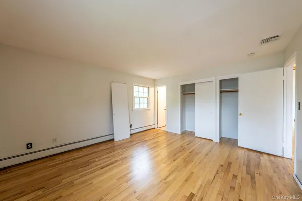 a view of an empty room with wooden floor and window