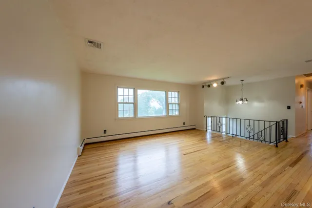 a view of an empty room with glass door and wooden floor