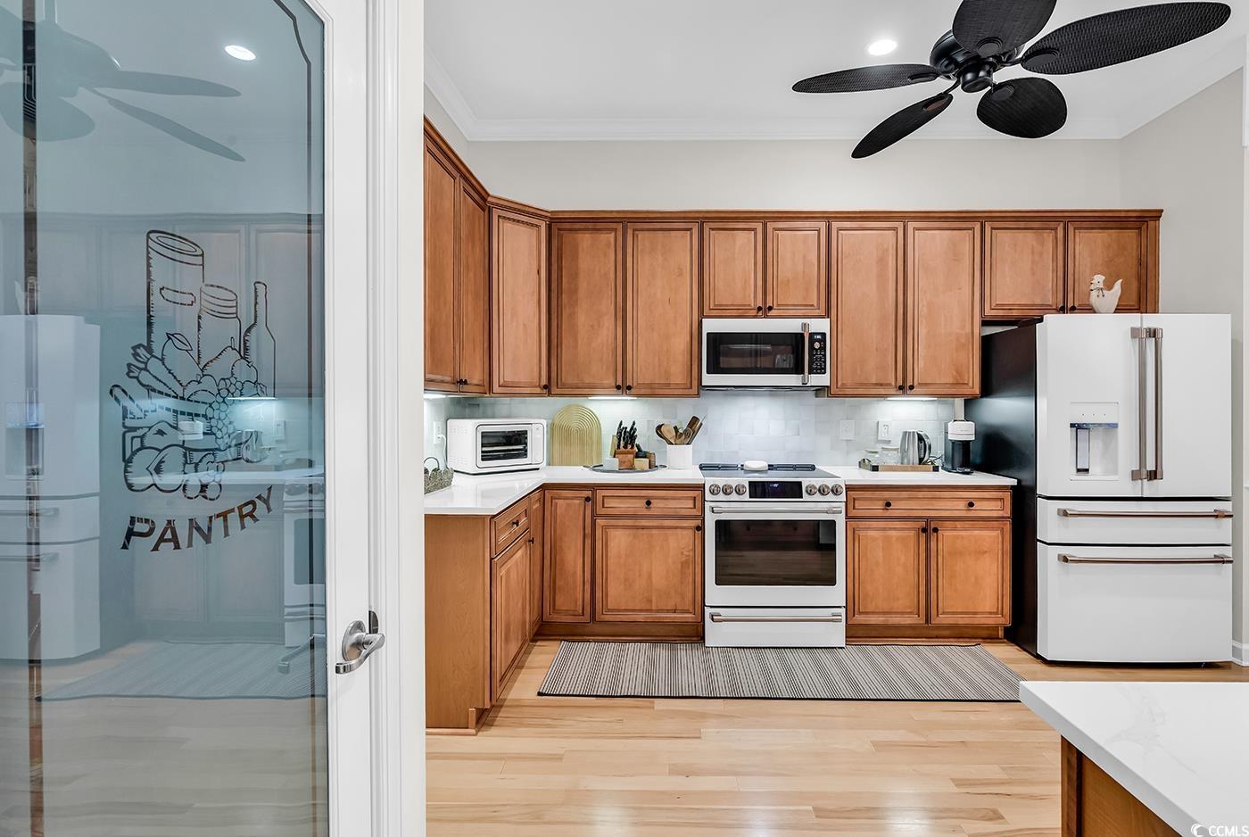 9 Saltwind Loop Murrells Inlet, SC 29576 - Photo 15 of 38 Kitchen with white appliances, a ceiling fan, brown cabinets, ornamental molding, and light wood-type flooring