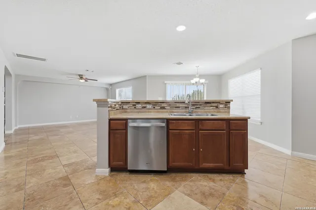 a room with kitchen island granite countertop a sink cabinets and stainless steel appliances