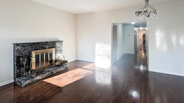 an empty room with wooden floor a chandelier fan and windows