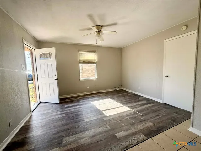a view of an empty room with window and wooden floor