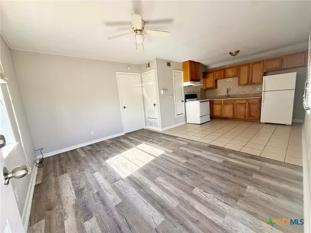 a view of a big room with wooden floor and windows
