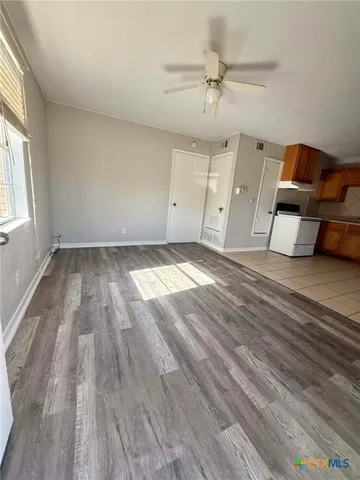 an empty room with wooden floor fan and windows