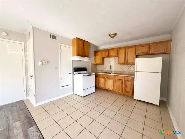 a kitchen with a refrigerator a stove top oven and white cabinets