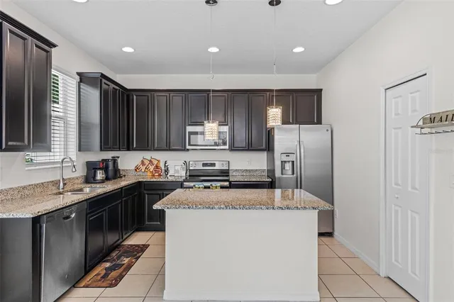 a kitchen with kitchen island granite countertop stainless steel appliances a sink stove refrigerator and cabinets