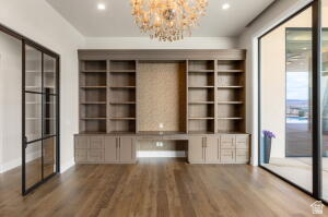 1141 East Lost Ridge Drive Washington, UT 84780 - Photo 52 of 108 Wood-finish flooring throughout this room featuring a crystal chandelier, built-in shelving with integrated cabinetry, and large black-framed glass doors