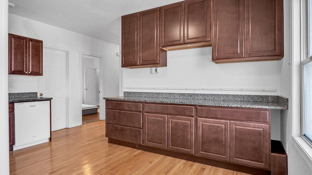 1442 Main Street, Unit 1 Worcester, MA 01603 - Photo 9 of 30 a kitchen with granite countertop wooden cabinets and white appliances
