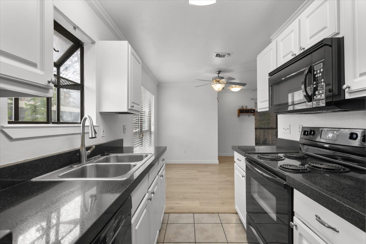 2018 West Rundberg Lane, Unit 9A Austin, TX 78758 - Photo 11 of 30 Kitchen featuring granite countertops, black electric range, microwave, updated cabinetry, bay window, dishwasher, and new refrigerator.
