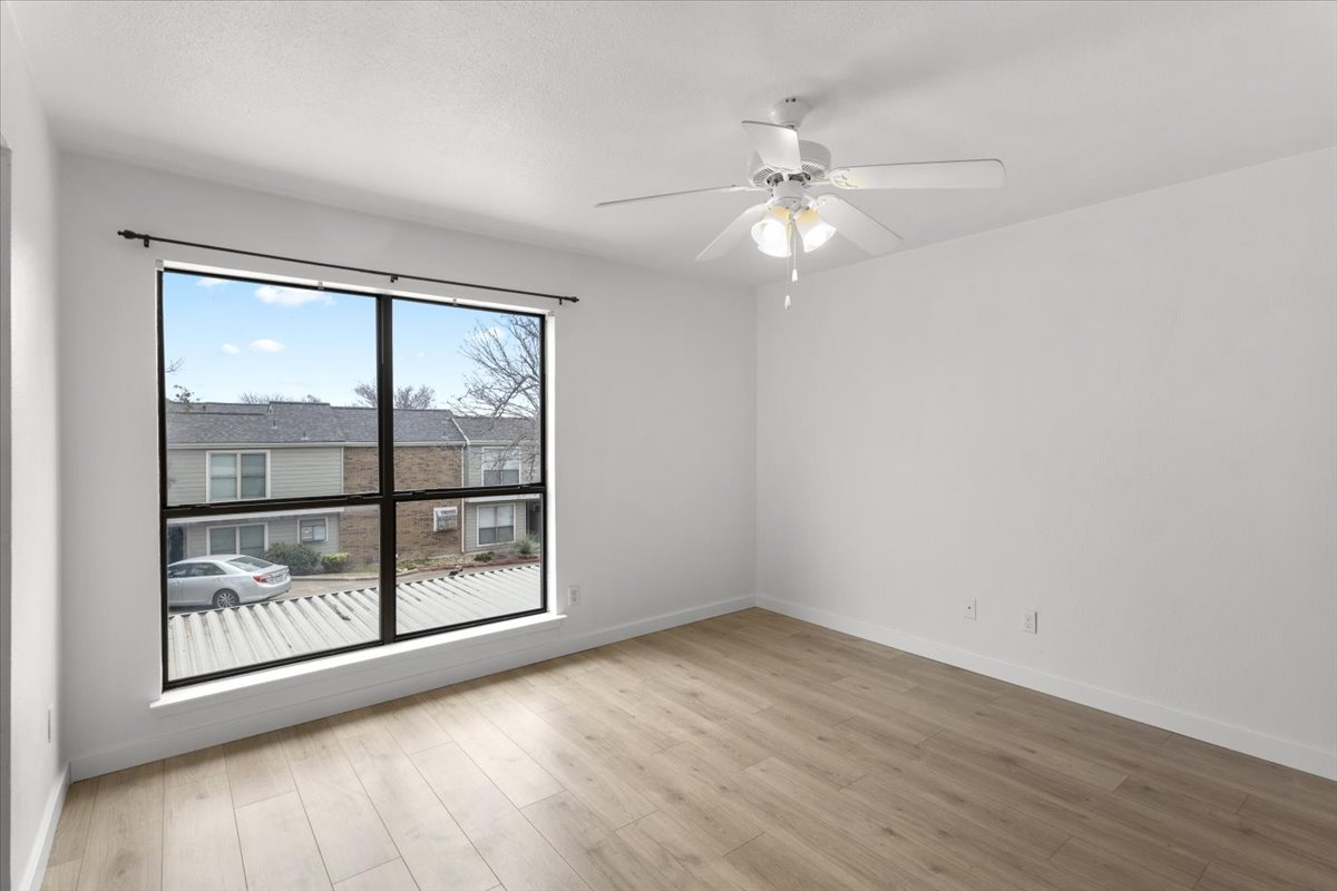2018 West Rundberg Lane, Unit 9A Austin, TX 78758 - Photo 19 of 30 1st floor bedroom featuring a ceiling fan and new engineered wood floors. Window faces east.