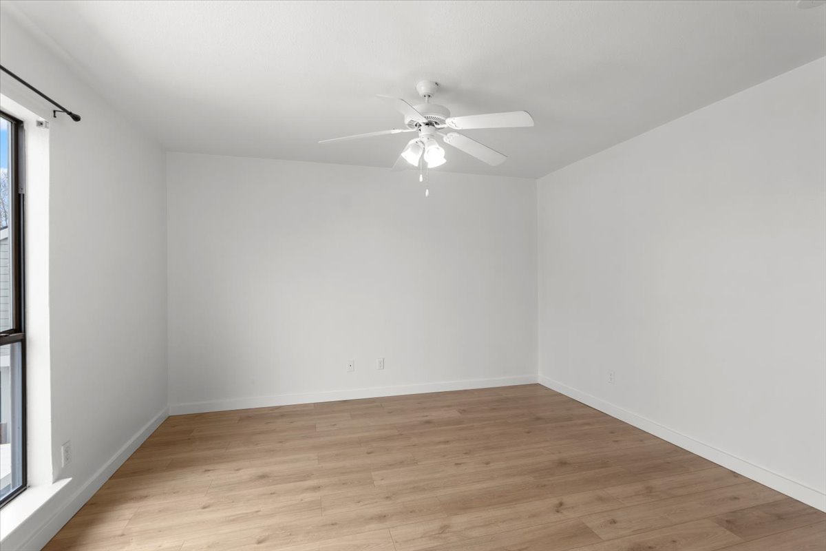 2018 West Rundberg Lane, Unit 9A Austin, TX 78758 - Photo 20 of 30 1st floor bedroom featuring a ceiling fan and new engineered wood floors. Window faces east.