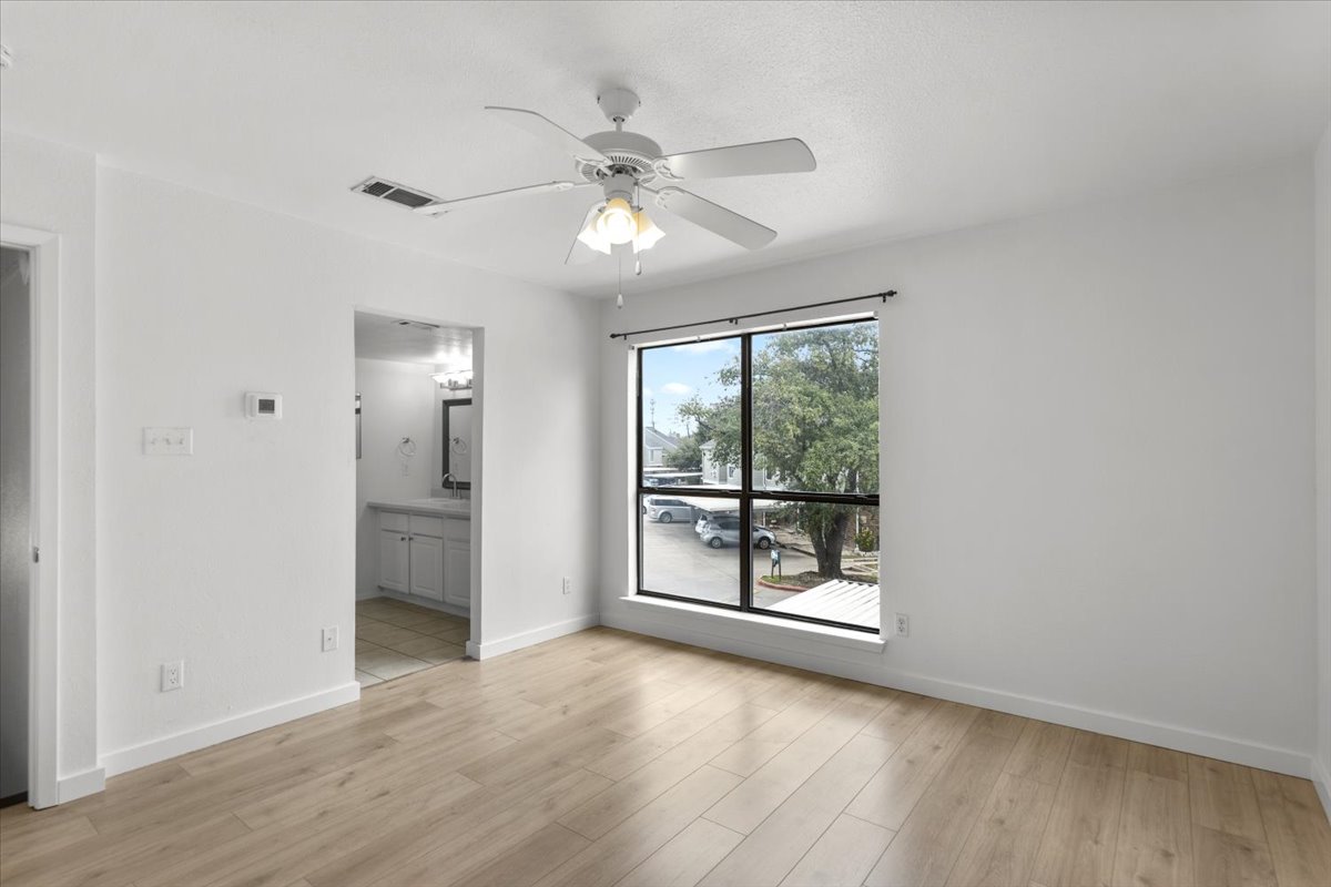 2018 West Rundberg Lane, Unit 9A Austin, TX 78758 - Photo 21 of 30 1st floor bedroom featuring a ceiling fan and new engineered wood floors and ensuite bathroom. Window faces east.