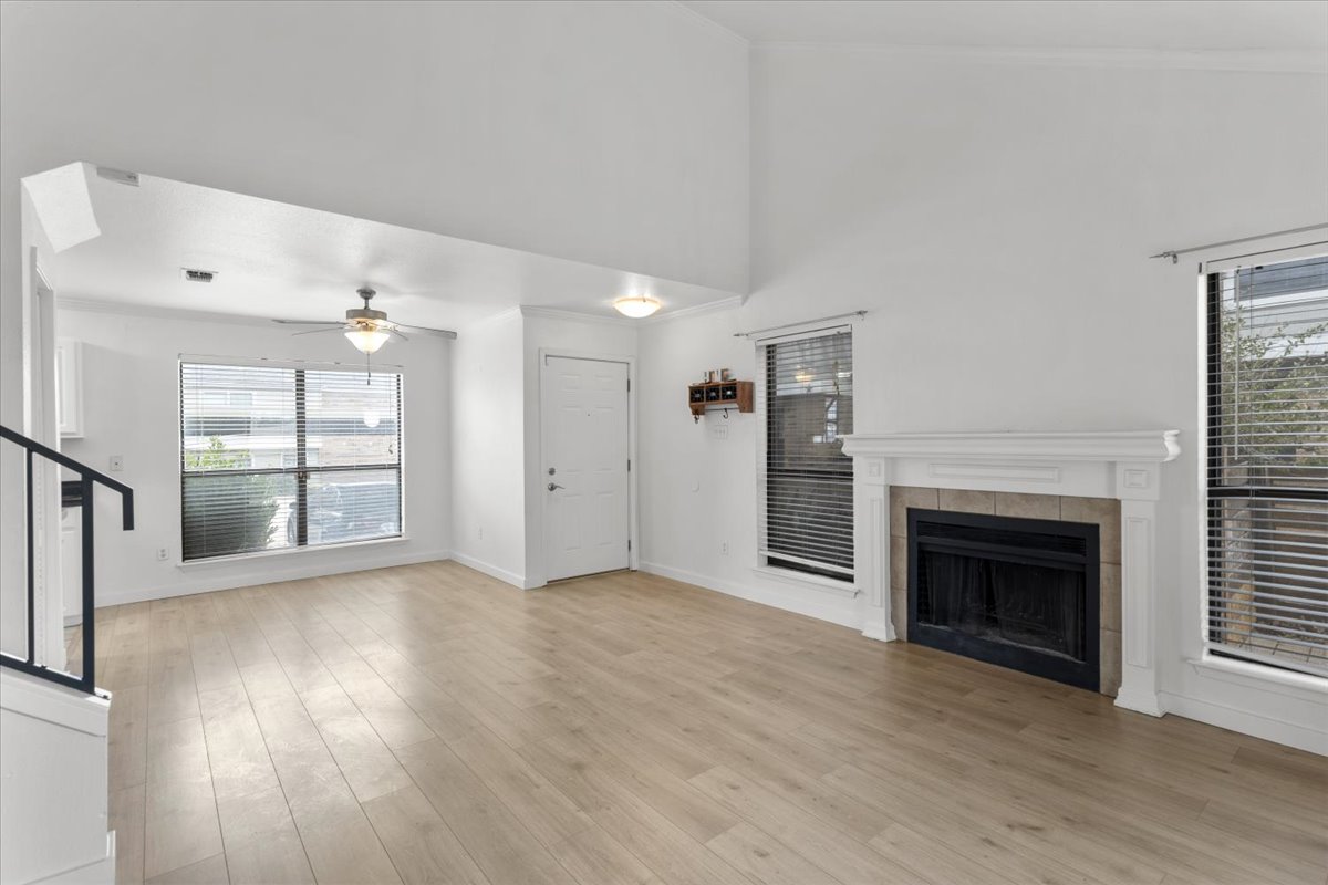 2018 West Rundberg Lane, Unit 9A Austin, TX 78758 - Photo 5 of 30 Living and dining rooms featuring light wood-style floors, lofted ceiling, a fireplace and windows on 3 sides.