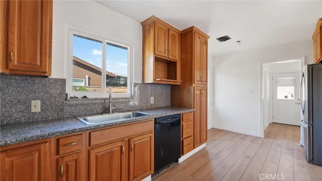 a kitchen with stainless steel appliances granite countertop a sink a stove cabinets and wooden floor