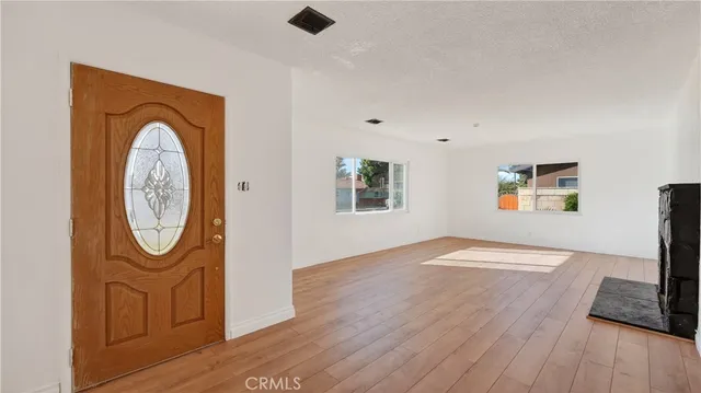 an empty room with wooden floor mirror and windows