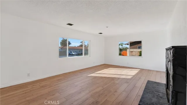 a view of an empty room with window and wooden floor