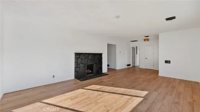 a view of empty room with wooden floor and fireplace