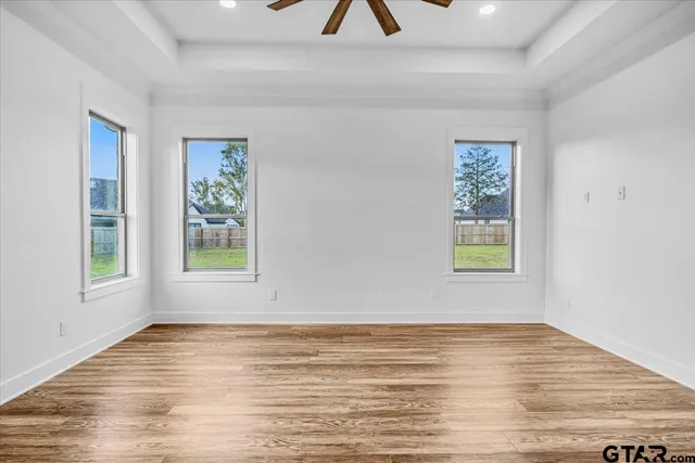 a view of empty room with wooden floor and fan