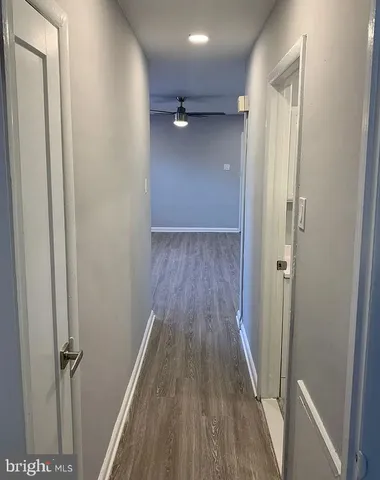 a view of a hallway with wooden floor and a ceiling fan