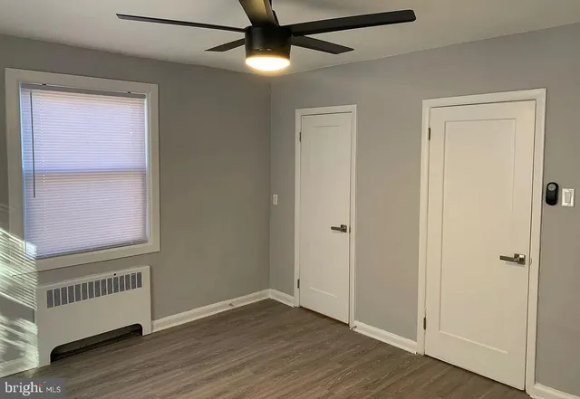 an empty room with wooden floor cabinet and windows