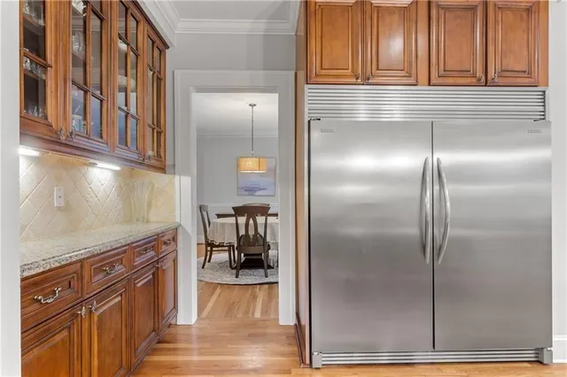 a kitchen with stainless steel appliances granite countertop a stove top oven a sink a dining table and chairs with wooden floor