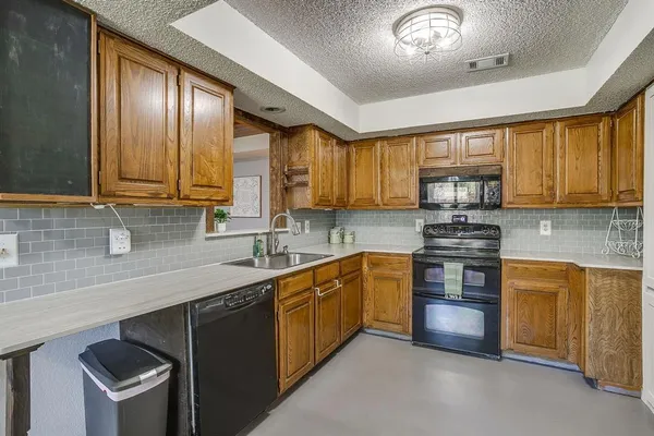 a kitchen with stainless steel appliances granite countertop wooden cabinets a sink a stove a refrigerator and dishwasher with wooden cabinets