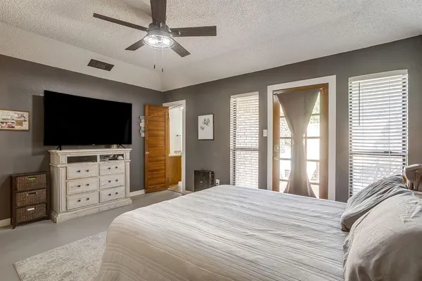 a bedroom with a bed television on dresser and a flat screen tv