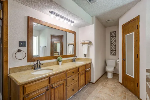 a bathroom with a granite countertop sink a toilet and a mirror