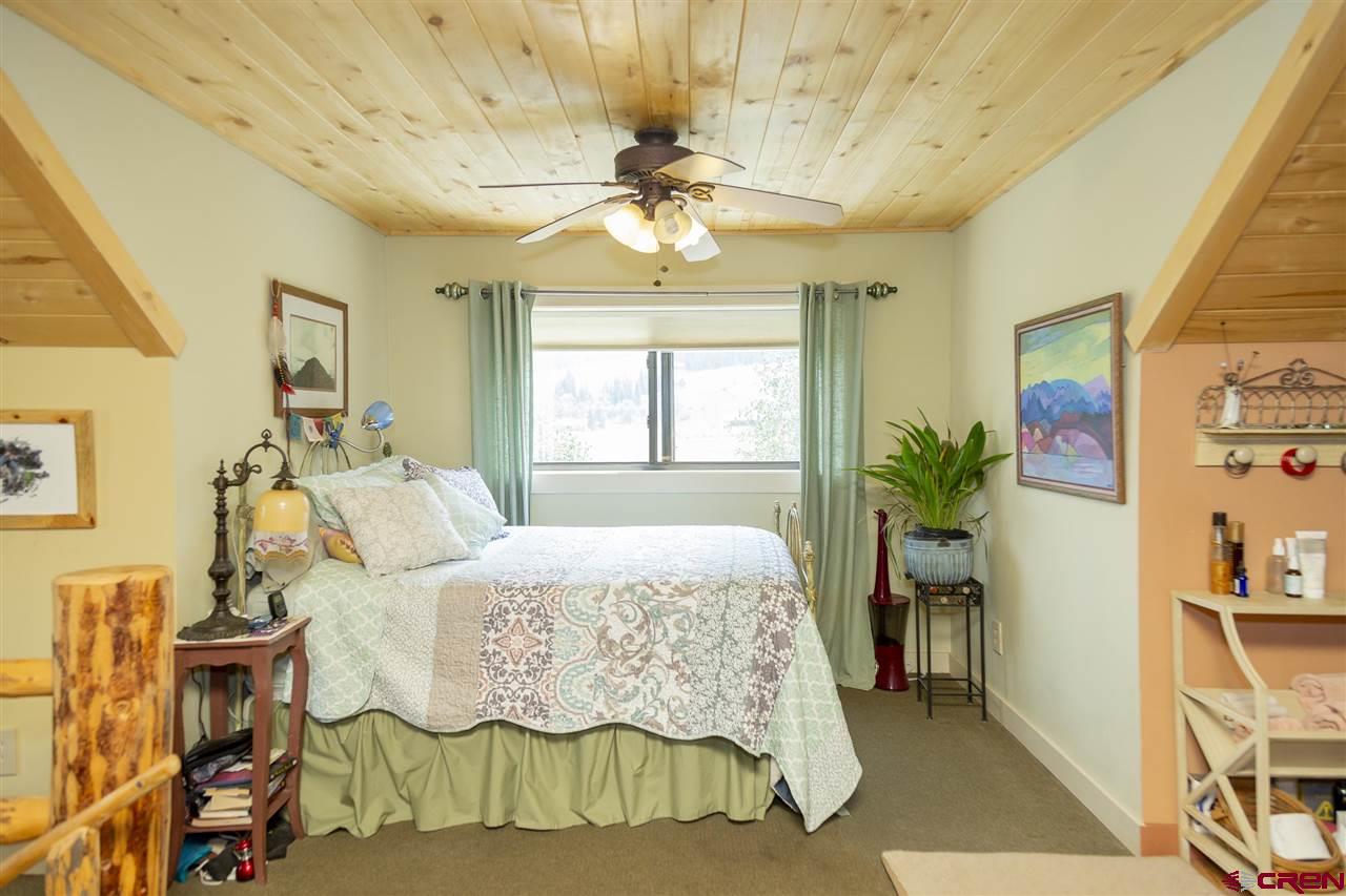148 Rio Grande Drive Creede, CO 81130 - Photo 5 of 27 a bedroom with a bed and a chandelier