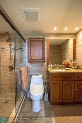 a bathroom with a granite countertop toilet sink and mirror