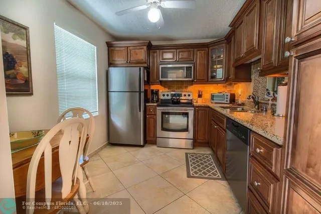a kitchen with stainless steel appliances granite countertop a refrigerator a stove and a sink