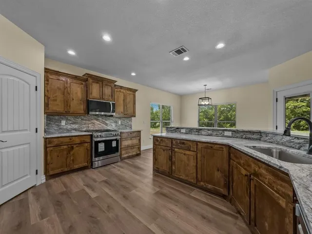 a kitchen with granite countertop a sink cabinets and wooden floor