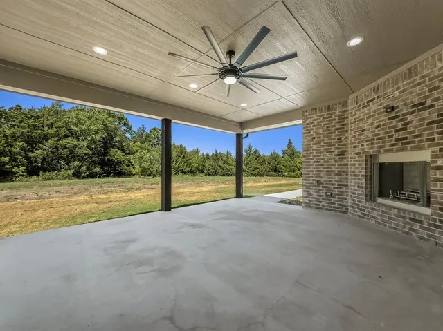 a view of an empty room with a fireplace and a ceiling fan